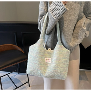 Detail of colorful knit tote bag featuring a white logo patch and soft woven texture