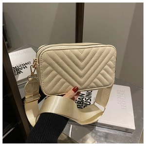Detail of beige quilted faux leather bag with elegant V-stitching and gold hardware
