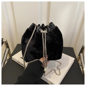 Detail der schwarzen Pelz-Eimertasche mit Silberkette und Perlenanhänger auf Büchern