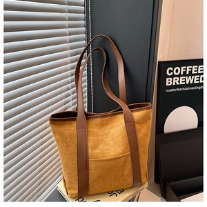 Detail of vintage suede tote bag in ginger yellow with brown leather straps and stitching