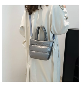 Quilted silver down fabric bucket bag with a lilac shoulder strap worn by a model
