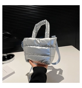 Vue détaillée du sac seau matelassé argenté avec bandoulière bleu clair et texture douce