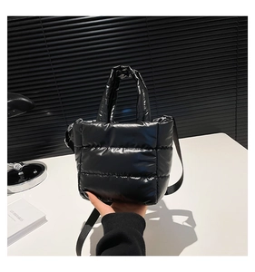 Détail d'un sac seau matelassé noir avec une bandoulière tissée réglable