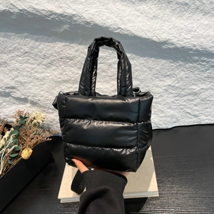 Minimalist black quilted down bucket bag with glossy nylon finish and shoulder strap