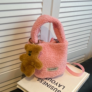 Sac seau rose en laine d'agneau avec breloque ours et bandoulière sur des livres