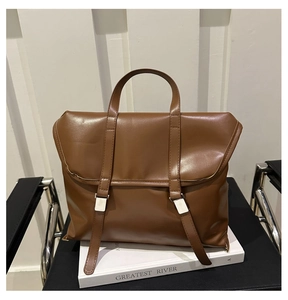 Close-up of brown leather handbag with vertical straps and silver metal buckle detail