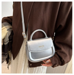 Mini sac à main argenté avec poignée et bandoulière porté par un mannequin