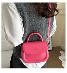 Vue détaillée du sac à bandoulière en cuir rose vif porté avec une sangle réglable