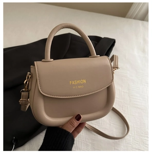 Close-up of beige crossbody bag with golden Fashion H.C Bag logo and elegant top handle