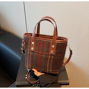 Detail of vintage plaid wool handbag with brown leather handles and golden metal rivets