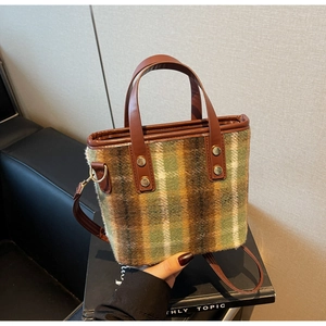 Detail of plaid wool tote with brown leather handles and gold metal rivets texture