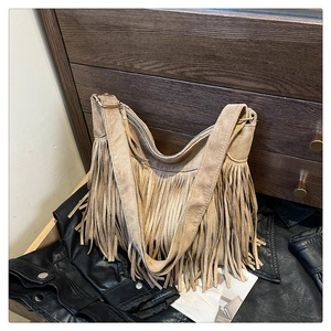 Detail of khaki suede tote bag featuring bohemian tassels and adjustable metal buckle strap