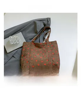 Detail of a brown corduroy tote bag featuring a red strawberry print for daily use