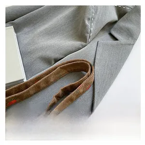 Detail of grey twill fabric tote bag featuring brown straps with red strawberry prints