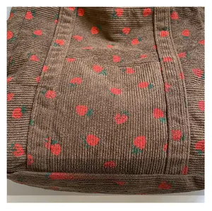 Macro shot of brown corduroy fabric texture and red strawberry print on tote bag