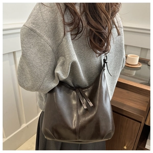 Detailed view of deep brown large capacity faux leather tote bag worn on shoulder