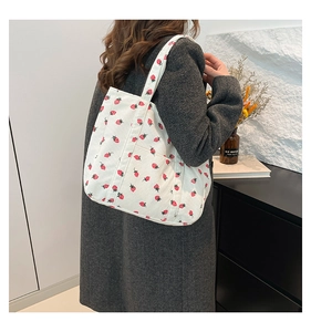 Detail view of white corduroy strawberry tote bag featuring a practical side pocket