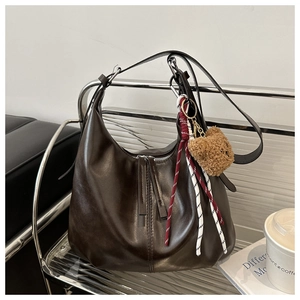 Detail of dark brown hobo bag with teddy charm on a modern chair with urban vibe