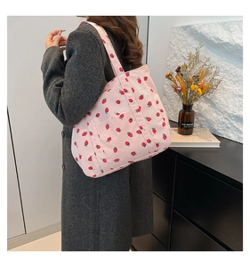 Pink striped corduroy tote bag with strawberry embroidery worn by a model in a grey coat