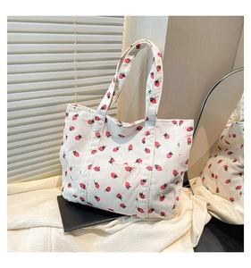 Close-up of strawberry print corduroy tote bag featuring a front pocket and soft texture