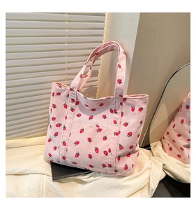 Detail view of pink corduroy tote bag with strawberry print and front pocket on white fabric