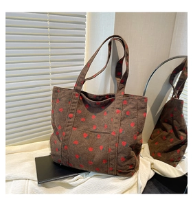 Detail of brown corduroy tote bag with red strawberry print on textured fabric