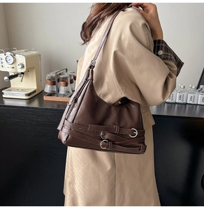 Dettaglio della borsa a spalla marrone vintage con cinturini decorativi e fibbie argento