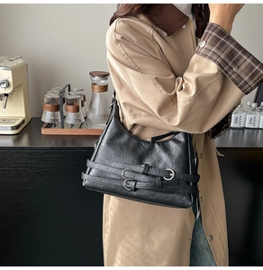 Dettaglio della borsa hobo nera con trama a pieghe e fibbie in metallo argentato