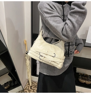 Dettaglio della borsa sottobraccio in pelle bianco crema con cinturini e fibbie