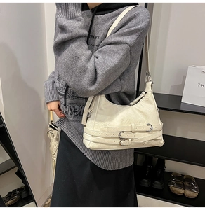 Dettaglio della borsa sottobraccio in pelle bianco crema con fibbie metalliche vintage