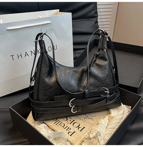 Dettaglio borsa hobo in pelle nera con trama vintage e fibbie in metallo argentato