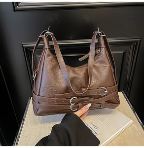 Dettaglio della borsa a mezzaluna marrone scuro con pelle stropicciata e anelli argentati