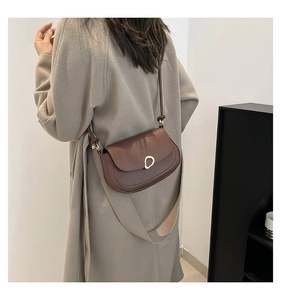 Detail of adjustable leather strap and golden buckle on retro brown saddle bag