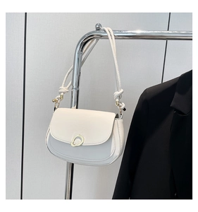 Detail of the minimalist off-white shoulder bag with elegant gold ring hardware and knotted strap