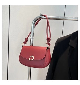 Detail of red saddle bag featuring unique gold buckle and knotted leather strap accent
