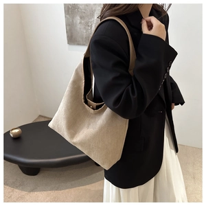 Gros plan sur un sac cabas en daim beige avec des lanières en cuir marron au style épuré