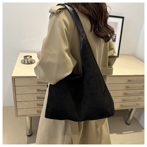 Détail du sac cabas en daim noir mat montrant la texture douce et la bandoulière en cuir
