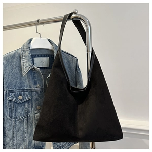 Détail du sac hobo en daim noir avec garniture en cuir suspendu sur un cintre