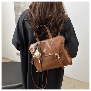 Vue détaillée d'un sac à dos rétro en simili cuir marron avec pendentif baseball