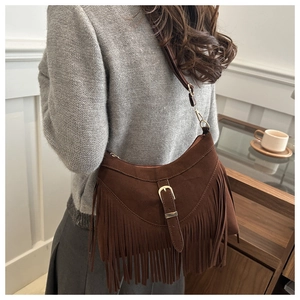 Detail of dark brown suede crossbody bag with long tassels and decorative metal buckle