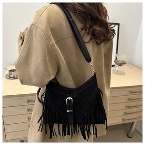 Chic black fringe tote bag featuring gold buckle and suede texture in a lifestyle setting