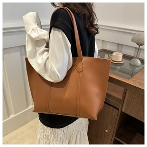 Close-up of caramel brown leather tote bag with vertical stitching and long shoulder straps