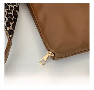 Close-up of golden zipper and stitching on leopard strap tote bag in brown leather