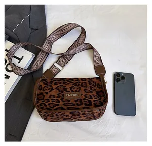 Detailed view of leopard print crossbody bag with fashion label and wide strap