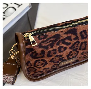 Close-up of smooth gold metal zipper and leopard print texture on crossbody bag