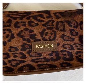 Detail of leopard print fabric with leather 'FASHION' patch and neat stitching on handbag