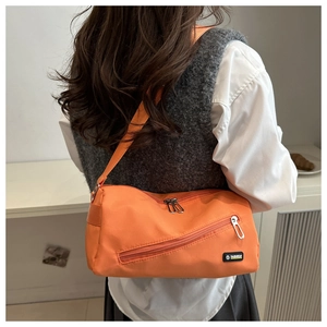 Vue latérale du grand sac bandoulière en nylon orange porté par un mannequin chic