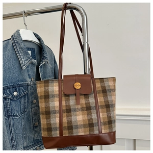 Detail of vintage brown plaid tote bag featuring leather base and antique metal magnetic buckle