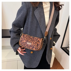 Detailed macro view of leopard print crossbody bag with woven strap and fashion label