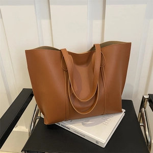 Minimalist brown leather tote bag with large capacity on a decorative chair